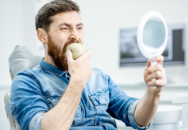 Men biting apple with dental implants